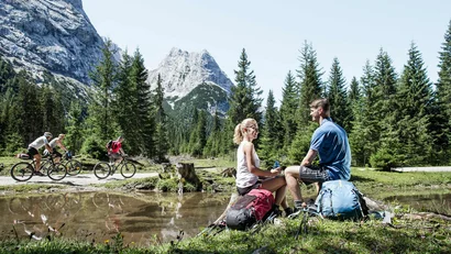 Couple resting during mountain hike with cyclists passing by