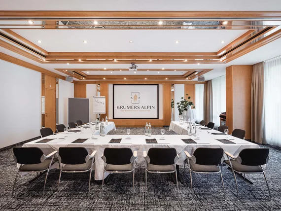 Conference room with tables, chairs, and presentation area at Krumers Alpin hotel