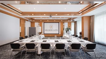 Conference room with tables, chairs, and presentation area at Krumers Alpin hotel