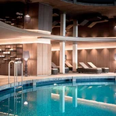Indoor pool view in a modern spa with lounge chairs and warm lighting
