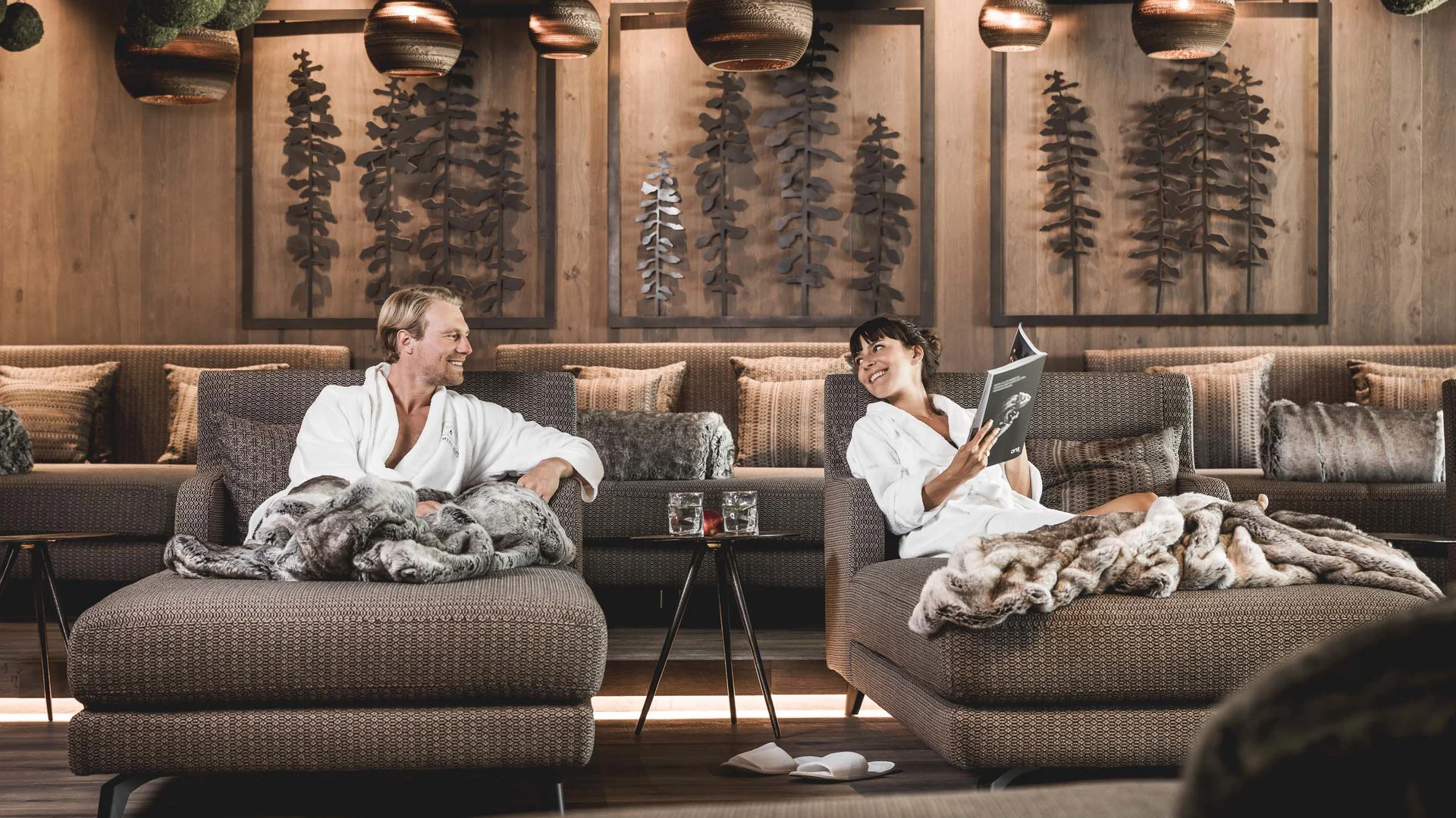 Couple relaxing in cozy lounge with blankets and warm wooden decor