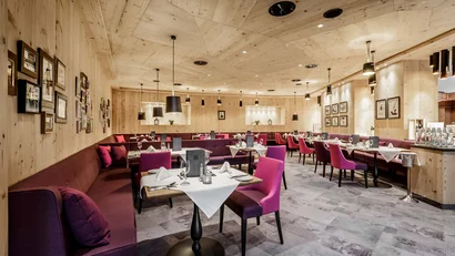 Elegant restaurant with wooden ceiling, purple chairs, and set tables