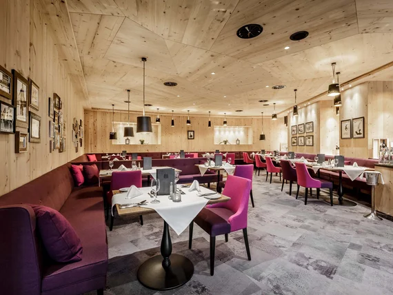 Elegant restaurant with wooden ceiling, purple chairs, and set tables