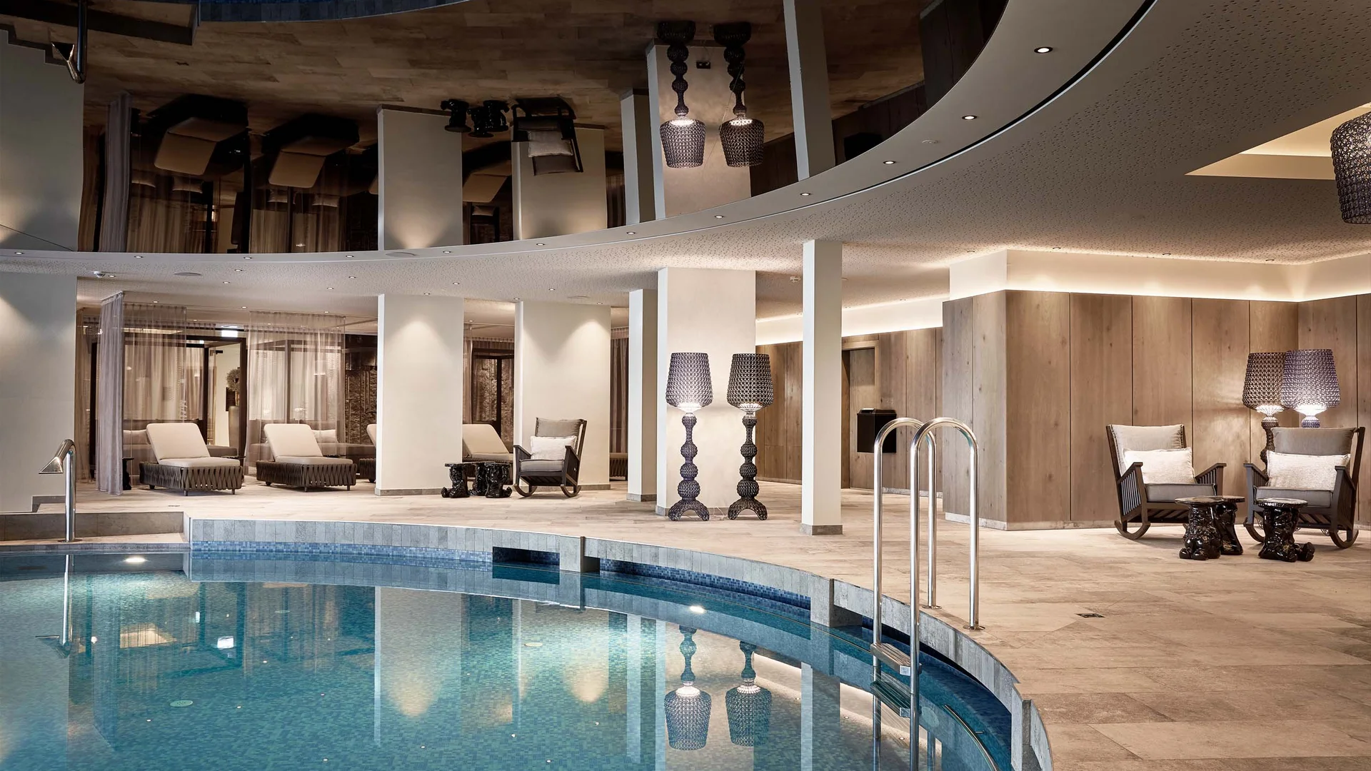 Interior view of a modern pool with lounge chairs and lamps