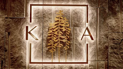 Illuminated logo with golden trees on stone wall