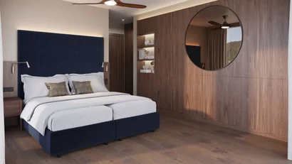Modern bedroom with blue upholstered headboard and large oval mirror