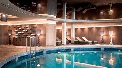Indoor area with heated pool, lounge chairs and modern lighting