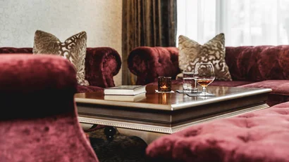 Elegant living room with red velvet sofas and table with book and drinks