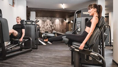 Man and woman exercising on leg extension machines in gym