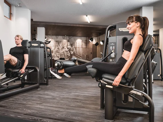 Man and woman exercising on leg extension machines in gym