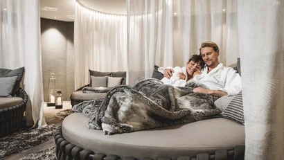 Couple relaxing on round sofa with blanket in modern room