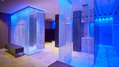 Glass tunnel with blue lighting and benches in modern interior